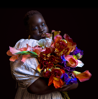 Low-light photo of a person holding a colourful bouquet of flowers.