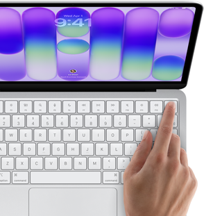 MacBook Neo, silver colour, showing login screen, person’s finger on Touch ID sensor in top-right corner of keyboard